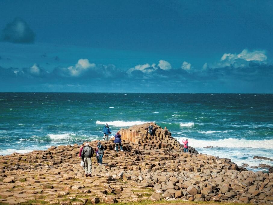 Visitors climb on the rocks near the water at Giants Causeway.
