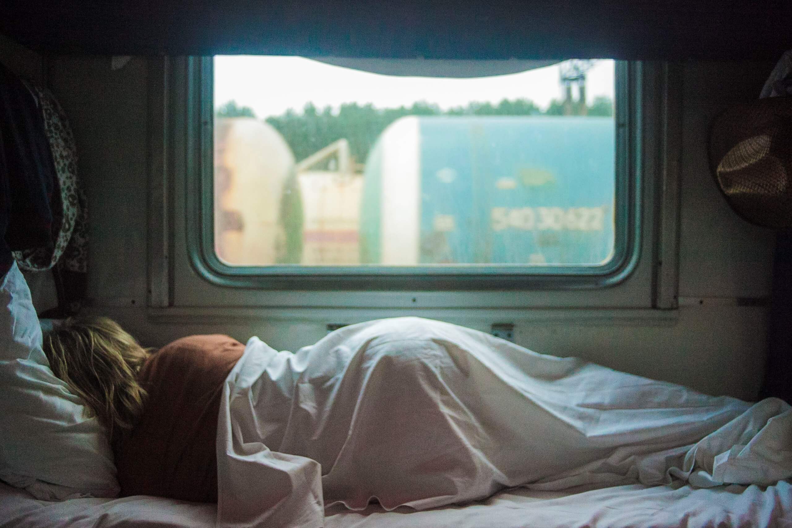 woman sleeping in a camper van alongside a window, expert tips for sleeping in strange beds and strange places, help me sleep.
