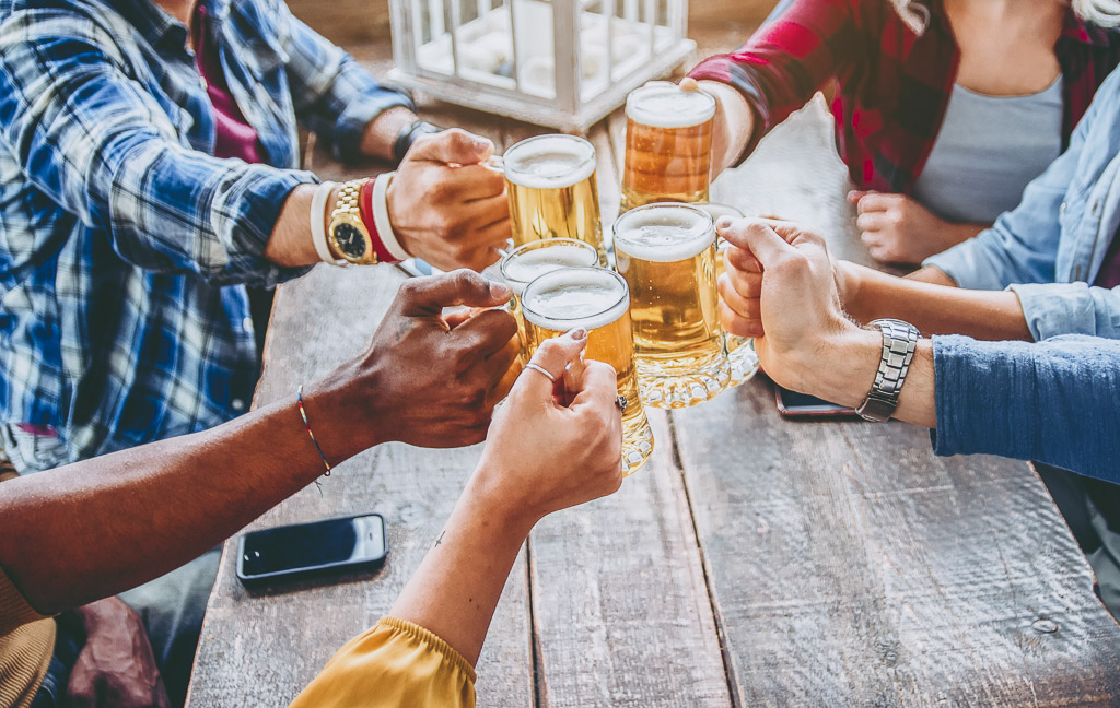 A group of friends toast with mugs of beers.