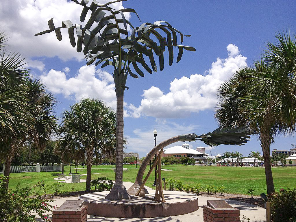 A sculpture on a green park lawn, with palm trees and a blue sea beyoond, one of the things to do in Punta Gorda